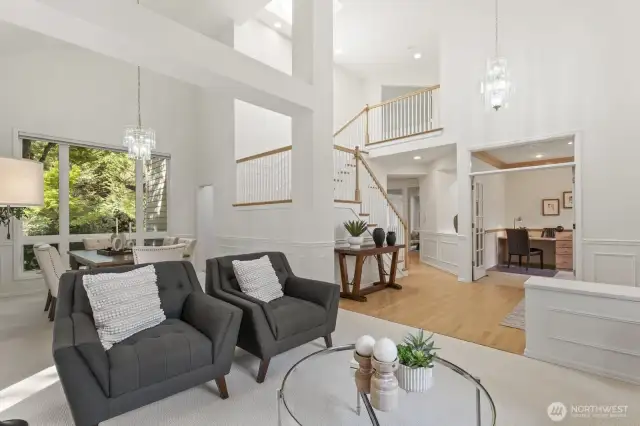 The formal living room with marble surround wood burning fireplace, tall vaulted ceiling and the formal dining room beyond.