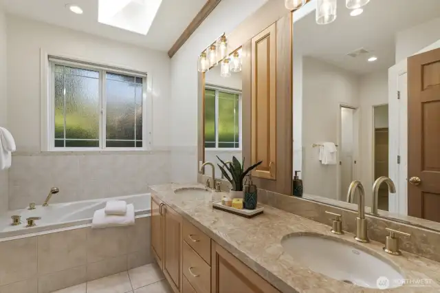In-law full bathroom with tiled floor, soaking tub and maple double vanity with travertine counter, undermount sinks and brushed brass faucets.