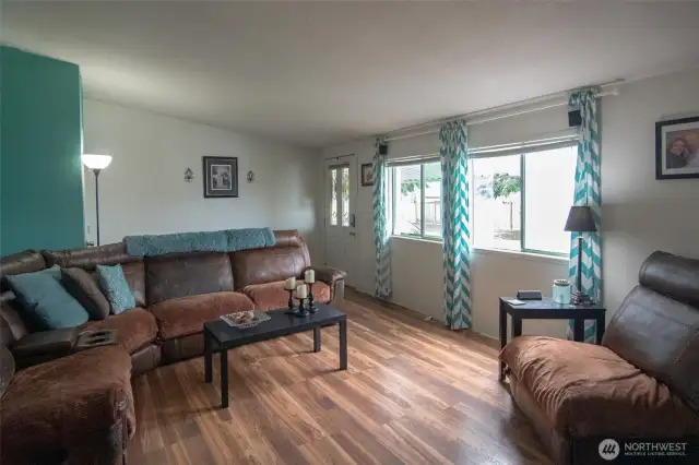 Enter to cheerful living room with laminate flooring and vaulted ceilings.
