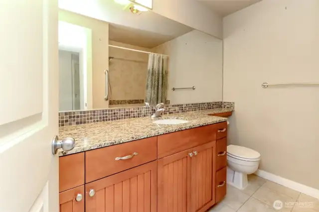 Classic granite tile countertops offer a polished and durable surface.  A backsplash trim is composed of decorative stone and glass mosaic pieces.