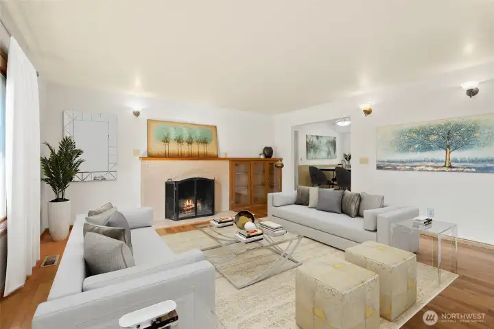 Sophisticated charm defines this home. The fireplace, framed by a pristine brick tile surround and flanked by built-in shelves, creates a focal point that radiates coziness, warmth, and positive energy. The open and airy flow of the family room is ideal for both daily living and entertaining, enhanced by large windows that invite in abundant natural light. A convenient coat closet welcomes you right by the entrance door, adding both function and practicality. Original wood flooring runs throughout, lending timeless elegance and durability, while fresh interior paint gives every room a crisp, updated feel.