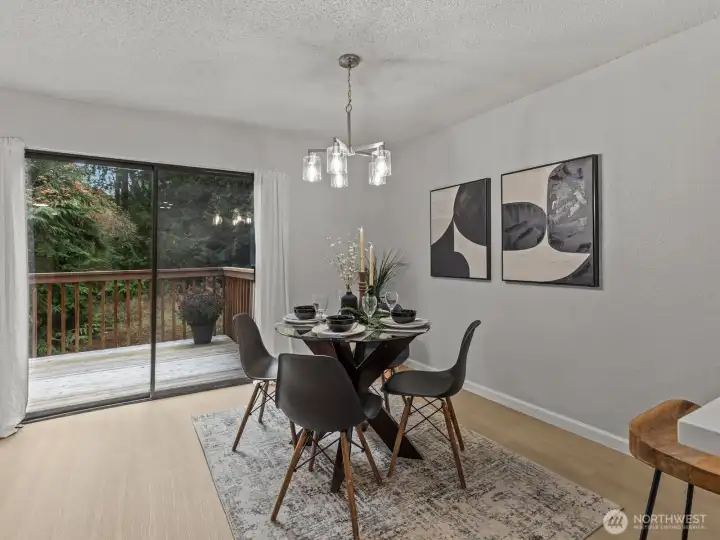 A sliding glass door provides access to the back deck, surrounded by mature trees.