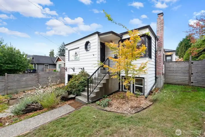 Charming updated exterior featuring crisp white siding with black trim, a welcoming front entry, and mature landscaping. Perfect blend of classic design and curb appeal