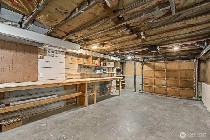 Spacious garage with concrete floors, built-in workbench, and ample shelving—perfect for projects, storage, or a home workshop