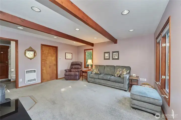 Exposed beams and recessed lighting highlight the character of this charming family room, while the wood-burning fireplace adds warmth and a welcoming ambiance.