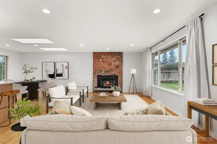 Floor-to-ceiling brick wood-burning fireplace with skylights and recessed lighting
