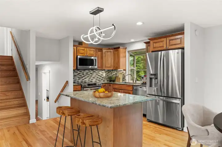 Kitchen island with granite countertops, bar seating, and sprial pendant light