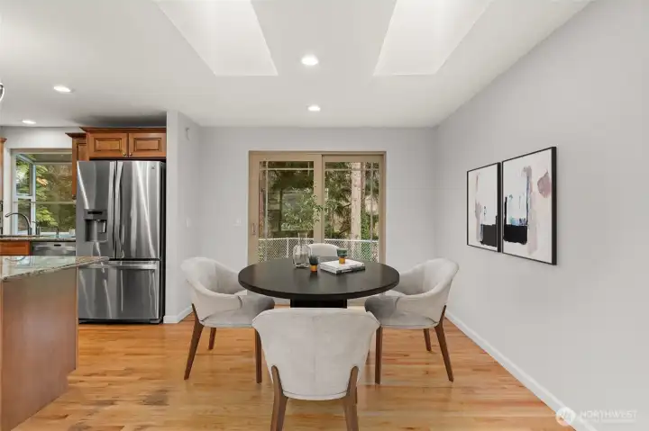 Dining area with sliding glass door to backyard — skylights above