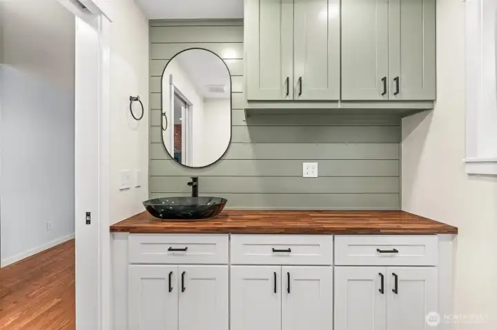 Gorgeous powder room — sage shiplap accent wall, butcher block counter, glass vessel sink