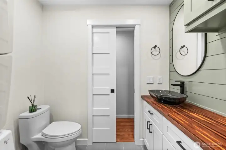 Powder room with space-saving pocket door, vessel sink, and butcher block workspace