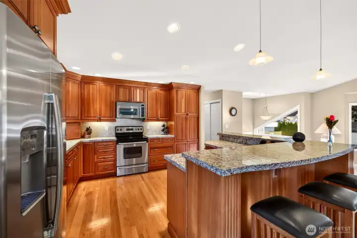 The kitchen is designed for function, with extensive cherry cabinetry, granite counters, and an oversized island that delivers standout prep space and serving room. Stainless appliances, recessed lighting, and a smart work triangle support everything from quick breakfasts to full holiday cooking.