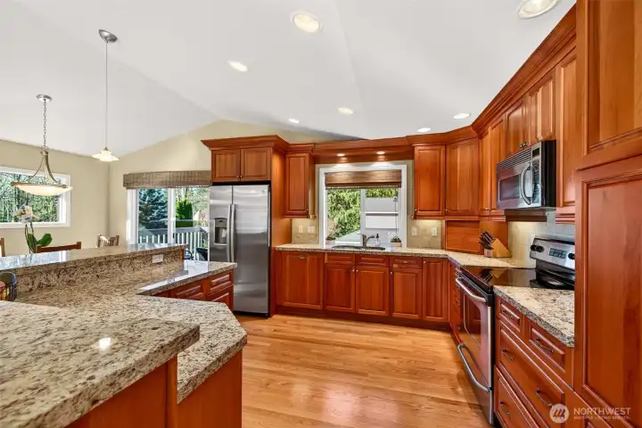 A closer look at the kitchen’s scale, granite surfaces stretch across multiple work areas, paired with ample cherry cabinetry for cookware, pantry items, and small appliances. The island creates a natural landing spot for casual meals, homework, and serving lines when friends are over.