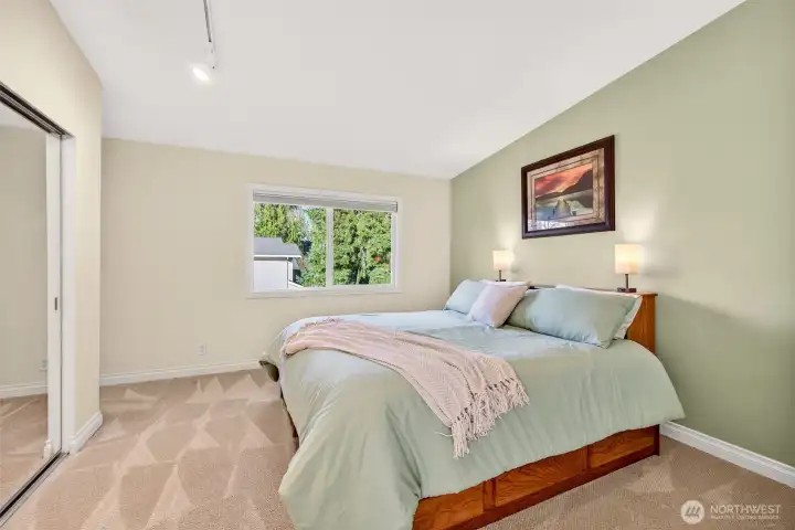 The primary suite offers a calm retreat with soft carpet underfoot, a large window that brings in natural light, and generous wall space for a variety of bedroom layouts. Mirrored closet doors add everyday function while keeping the room feeling open and bright.