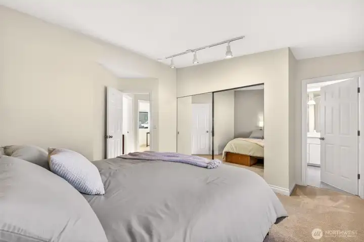 Another view of the primary suite highlights the thoughtful flow, with easy access to the ensuite bath and abundant closet storage. Track lighting and clean lines create a comfortable, move in ready space designed for restful nights and easy mornings.