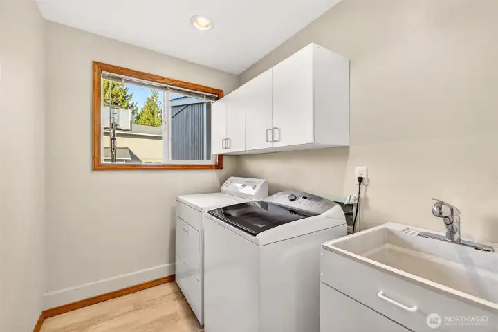 Dedicated laundry room with extra storage cabinetry and a utility sink that adds real everyday function. The window brings in daylight, and the layout provides practical space for sorting, folding, and keeping supplies organized.