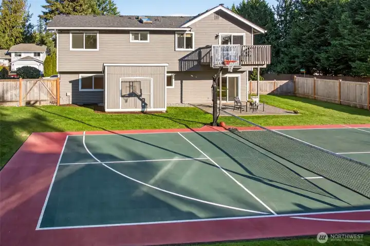 A true backyard lifestyle setup, featuring a multi use sports court for basketball, pickleball, and practice sessions, surrounded by a level lawn and full fencing for privacy.