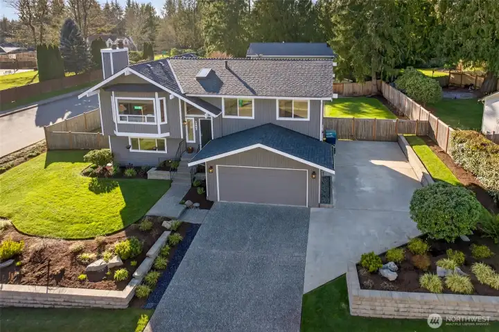 Aerial curb appeal shows the home’s inviting split level design, established landscaping maintained by a sprinkler system, and a spacious driveway that sets the property apart. The attached two car garage and additional parking area deliver everyday convenience, while the large lot provides room to spread out, inside and out, with the added confidence of a new roof in 2025.