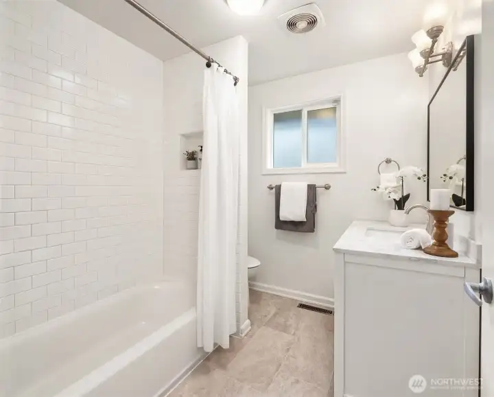 Remodeled bath showcasing wainscoting and updated vanity.