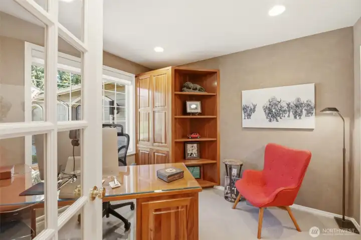 French doors lead you into a home office space with custom cherry cabinetry and desk, built by Crest Cabinets