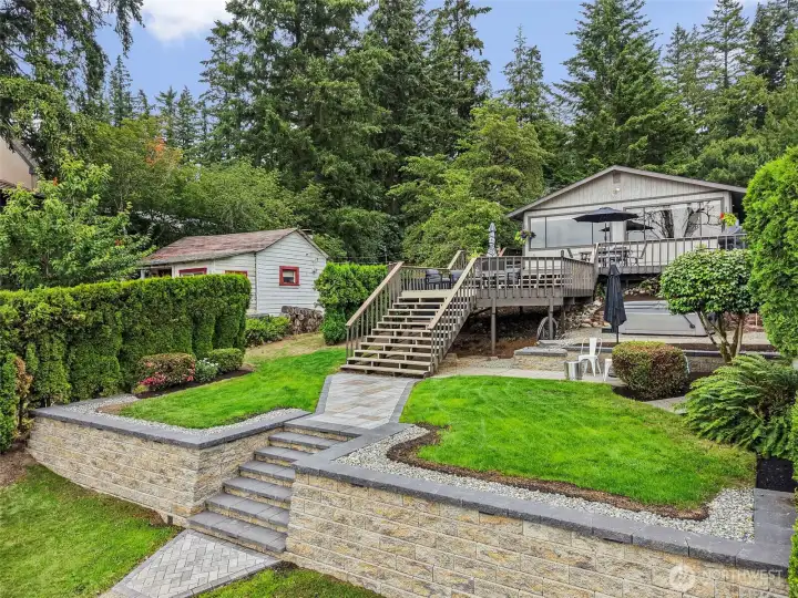 Terraced lakefront yard with stairs, lawn space, and storage shed.