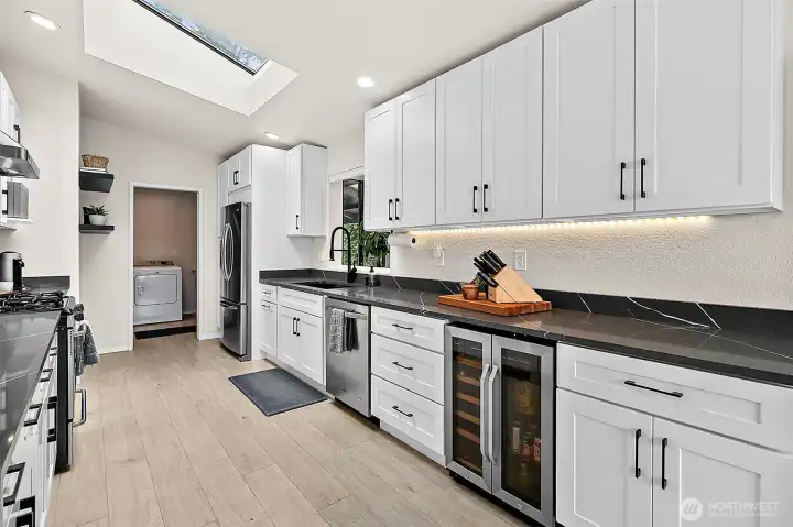Kitchen with sleek counters, under-cabinet lighting, beverage fridge, and generous cabinet storage.