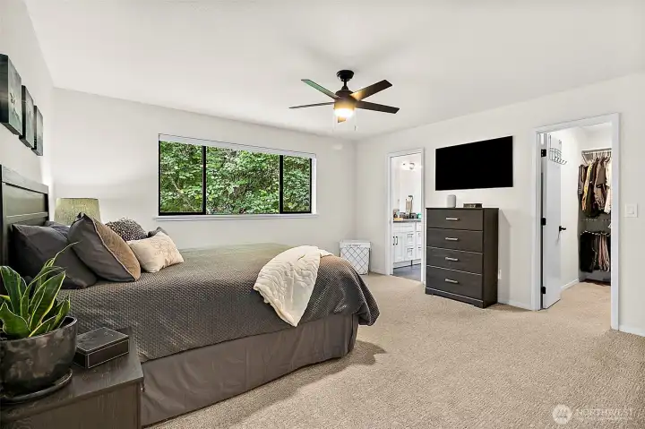 Spacious primary bedroom with ceiling fan, large window, and closet access.