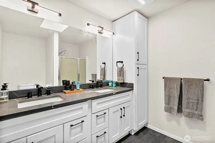 Full bathroom vanity with large mirror, updated counter, and bright lighting.