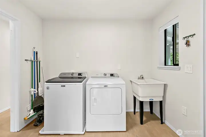 Laundry room with washer, dryer, utility sink, and added storage space.