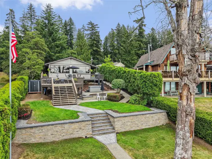 Lakefront exterior with two-tier deck, lawn, patio space, and dock access.