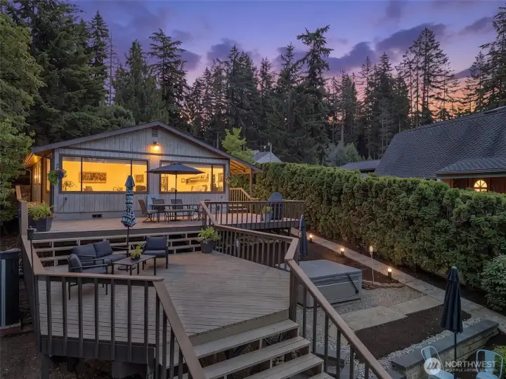 Twilight view of the two-tier deck, hot tub area, and warm lakefront entertaining space.