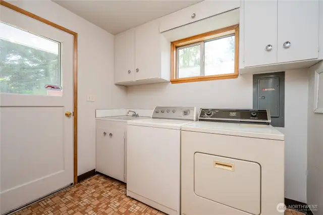 The Laundry Room features a utility sink, washer & dryer, plenty of storage in cabinetry & a spacious pantry to the rear in this photo.