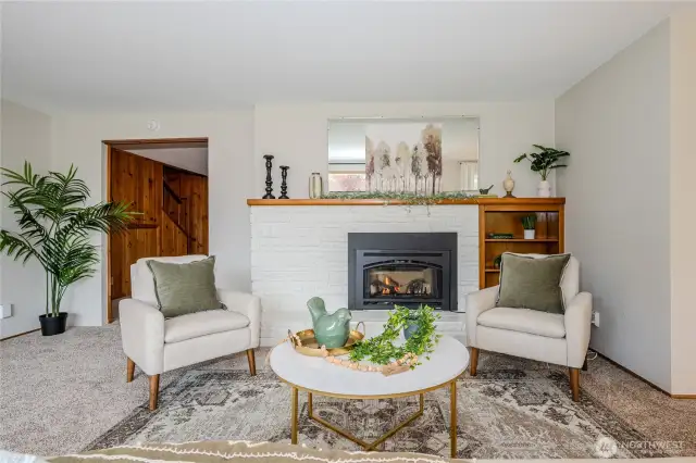 A cozy gas fireplace provides warmth and ambiance to this space. Notice the doorway to the Family Room on the left.  Dining Room and Kitchen are to the right. And a hallway to bedrooms is to the far left.