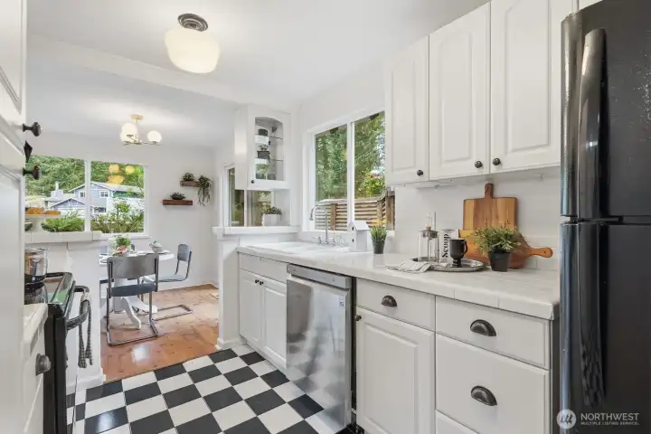 Kitchen offers white cabinetry, tile counters and flooring, and a charming, inviting feel.