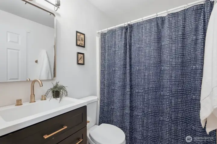 Updated ensuite primary bath offers tile flooring and refreshed finishes, including updated lighting, mirror, vanity, sink, and hardware.