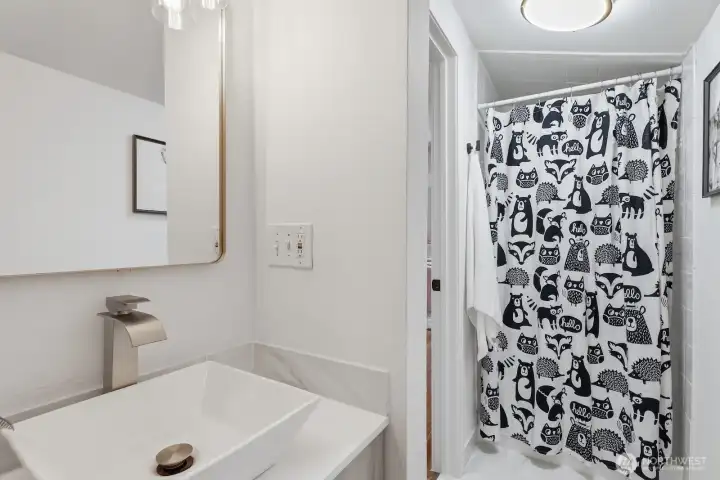 Freshly updated upstairs ¾ bath offers tile flooring, new vanity, sink, faucet, hardware, and a tile shower.
