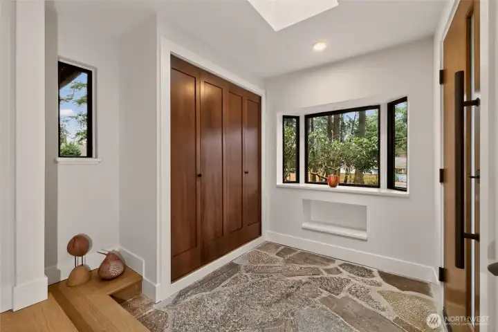 Welcoming entryway features an east-facing custom solid wood door, original stone floors, a skylight, a bay window, a large coat or storage closet, and a cubby niche. Welcoming entryway features an east-facing custom solid wood door, original stone floors, a skylight, a bay window, a large coat or storage closet, and a cubby niche.