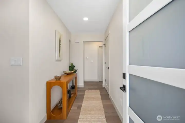 Welcoming entry hall with modern front door, updated flooring, new trim, and warm natural styling.