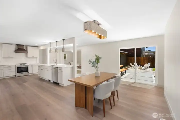Open-concept kitchen and dining area with abundant natural light, custom cabinetry, designer lighting, and new stainless appliances.