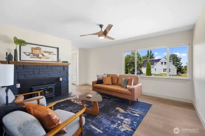 Separate den with wood-burning fireplace, modern finishes, ceiling fan, and a cozy second gathering space