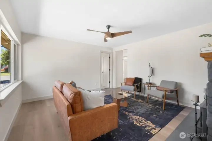 Separate den with wood-burning fireplace, modern finishes, ceiling fan, and a cozy second gathering space