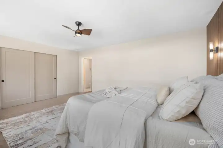 Oversized primary suite with custom wood feature wall, integrated accent lighting, designer sconces, and warm modern finishes.