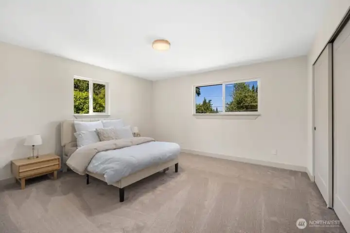 Generous secondary bedroom with new carpet, updated lighting, large windows, and flexible furniture placement.