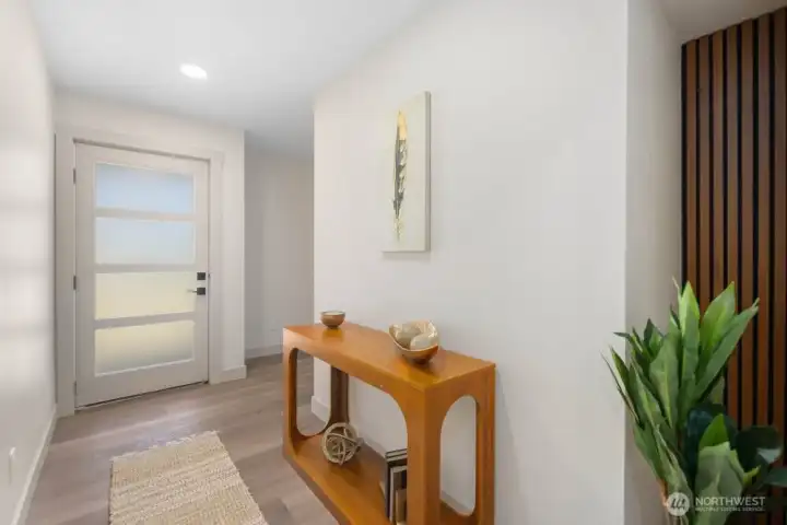 Wide central hallway with warm flooring, modern doors, updated trim, and thoughtfully styled entry details.