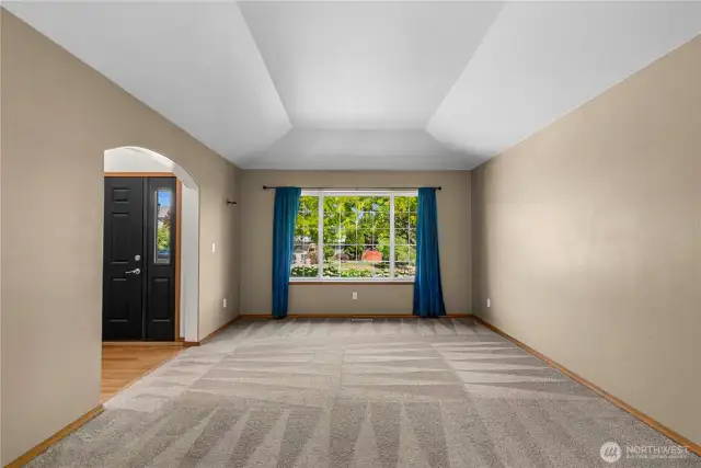 Open concept living and dining room with decorative tray ceilings.