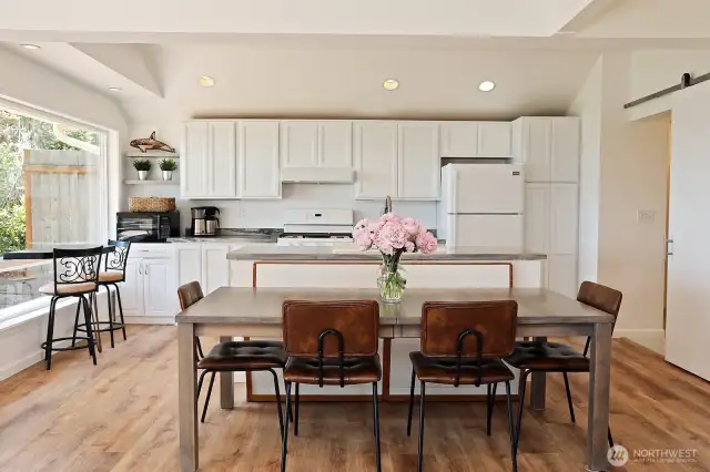 Vaulted ceilings with an open concept living/dining area, barn door along the right edge of the photo opens to a 3/4 bathroom and laundry room.