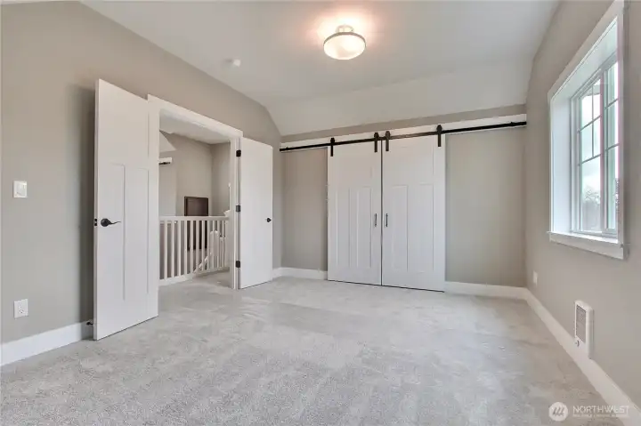 Guest bedroom with French doors at entry and barn doors for closet/storage area.