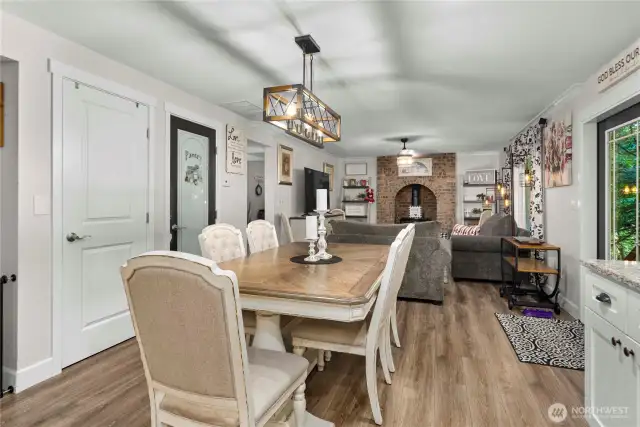 The dining area is huge and seamlessly connects the chef's kitchen to the cozy second living room featuring a brick-surround propane stove.  Walk-in pantry shown to the left, and further down is the entrance to the main floor 2 bedrooms, full bath, and laundry with an additional half bath.