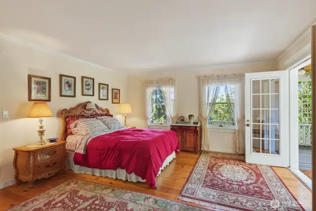 Main Level Primary bedroom with French doors opening to a covered sitting area