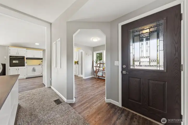 View of entry, formal dining room and kitchen. This shot captures the flow between the entry highlighting the natural light and connection between the spaces.