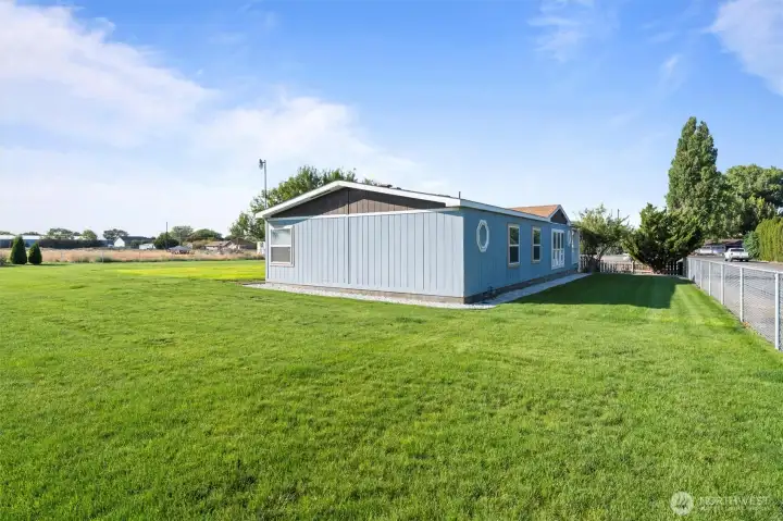 Side view of house and beautiful backyard with lush greenery and potential for outdoor entertaining.
